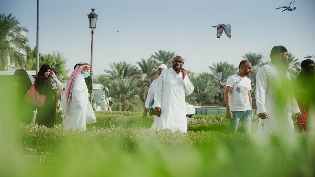 People walking in a public square in Saudi Arabia, traditional white thobes and palm trees