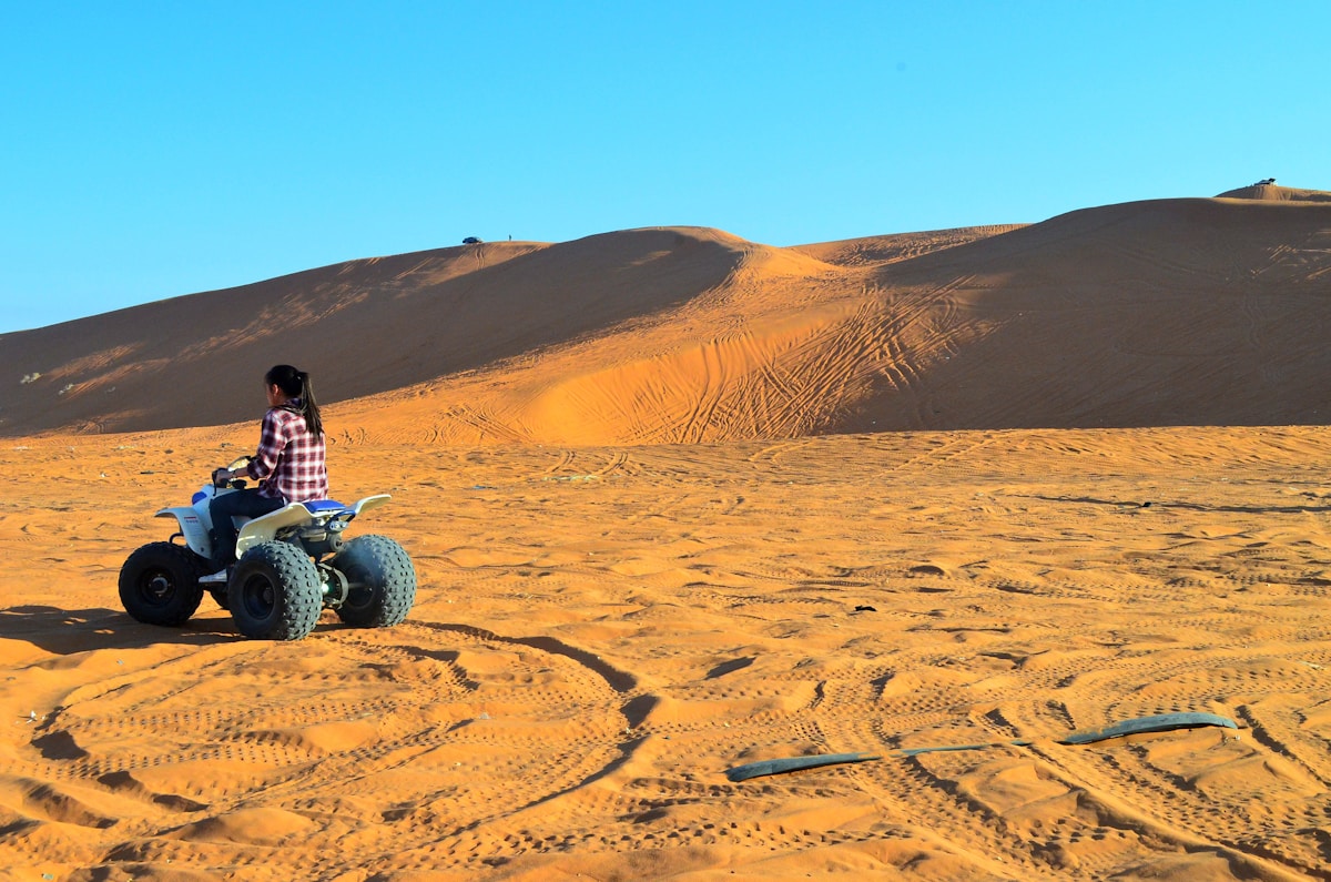 Person on ATV quad bike riding across red sand dunes near Riyadh, Saudi Arabia