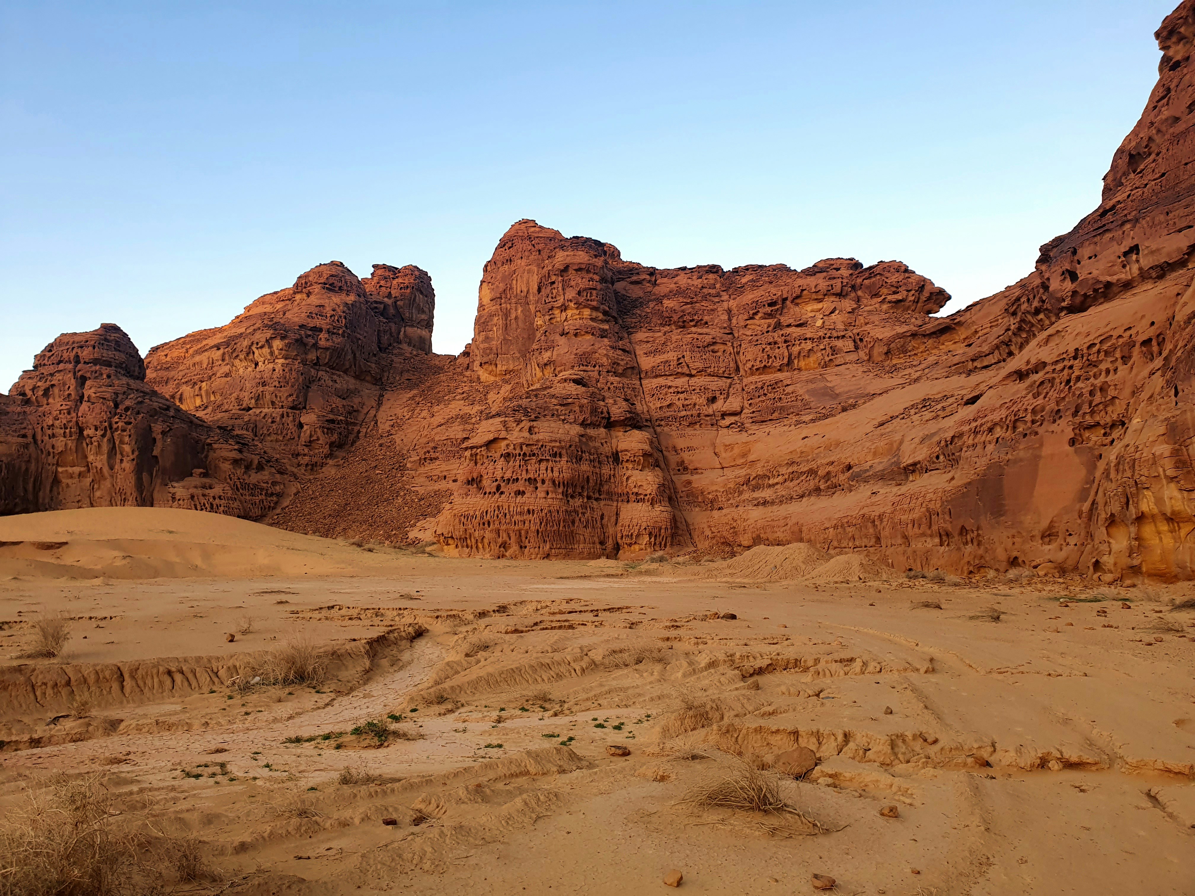 Red sandstone rock formations rising from golden desert sand at AlUla, Saudi Arabia
