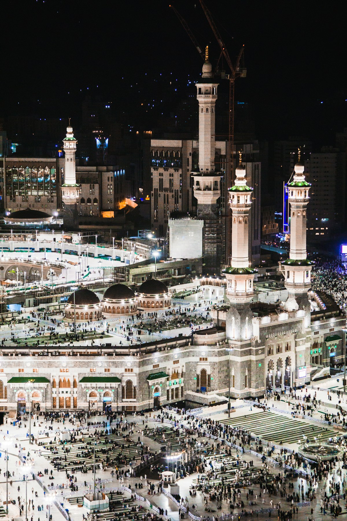 Grand Mosque in Mecca illuminated at night with minarets and worshippers, Saudi Arabia