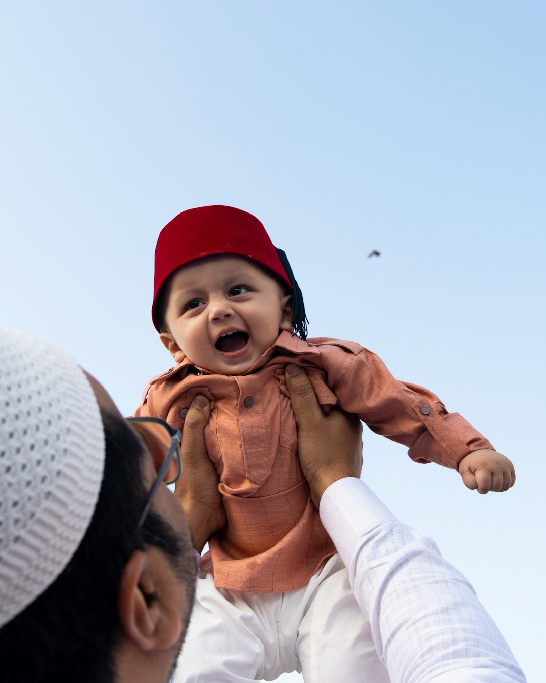 Happy child in traditional red fez hat celebrating Eid with family