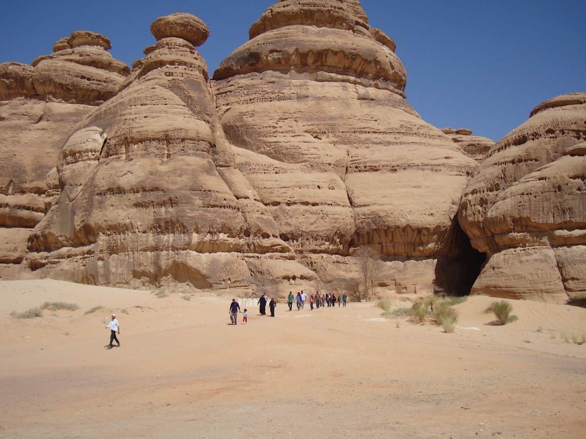 Visitors walking through Nabataean sandstone rock formations at Hegra (Madain Saleh) near AlUla, Saudi Arabia