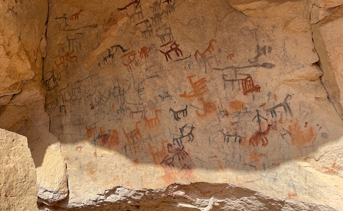 Ancient petroglyphs of humans and animals carved into a sandstone face at Jubbah in the Ha'il region