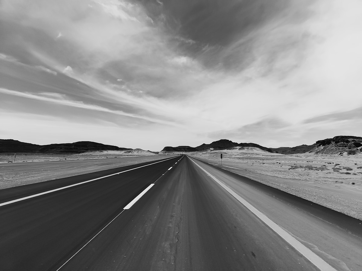 Desert highway stretching toward sandstone mountains in northwestern Saudi Arabia