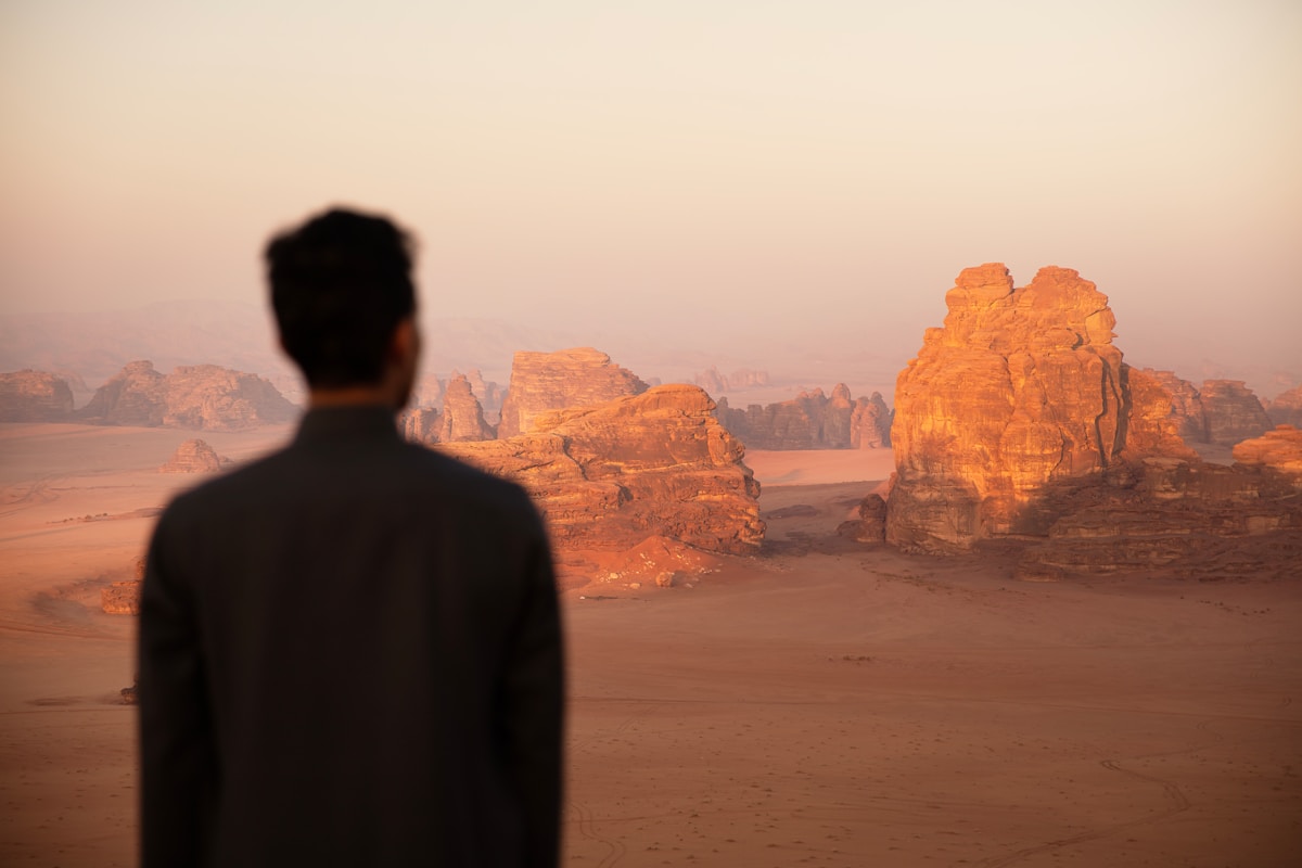 Traveller overlooking the sandstone formations of the Hisma Desert, Saudi Arabia at sunset