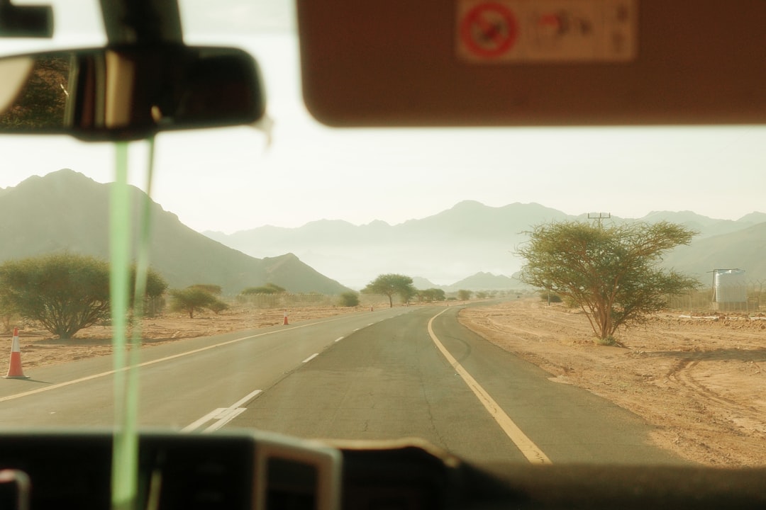 View from inside a vehicle driving along a desert road in Saudi Arabia, mountains in the background