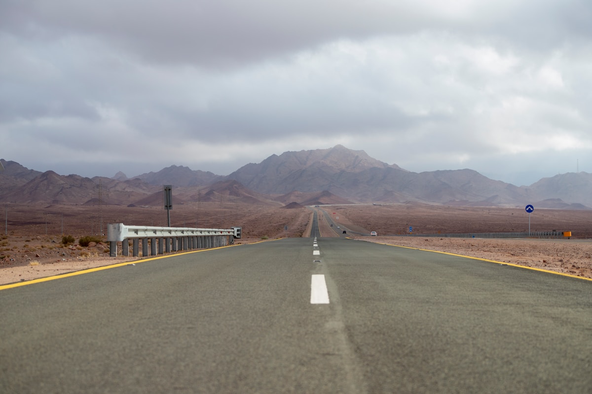 Empty desert highway stretching towards mountains in Saudi Arabia, clear road ahead