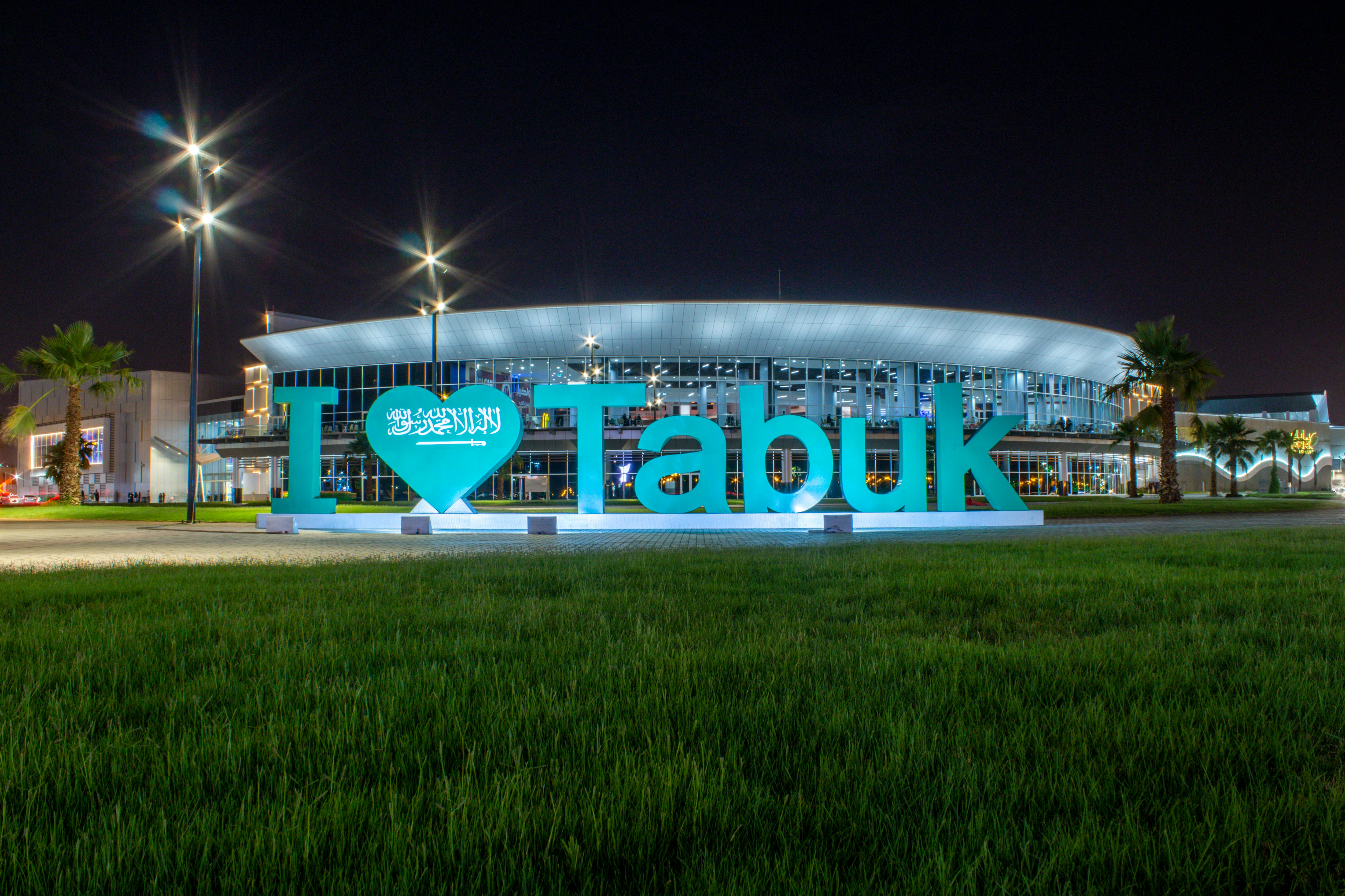 I Love Tabuk illuminated sign at night with a modern building behind, Tabuk city, Saudi Arabia